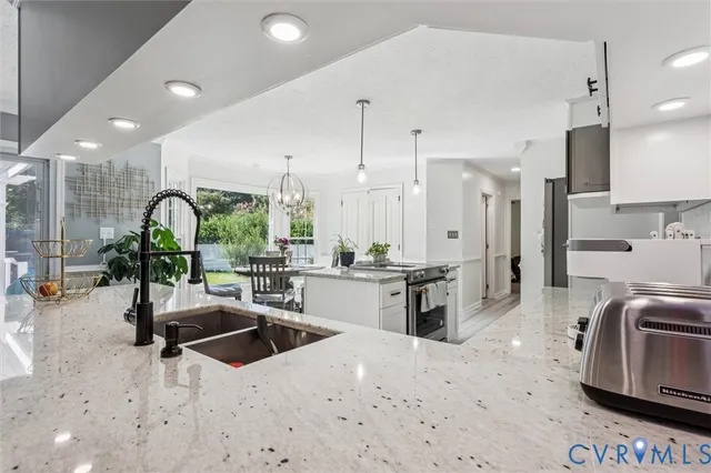 a kitchen with stainless steel appliances kitchen island granite countertop a sink refrigerator and cabinets