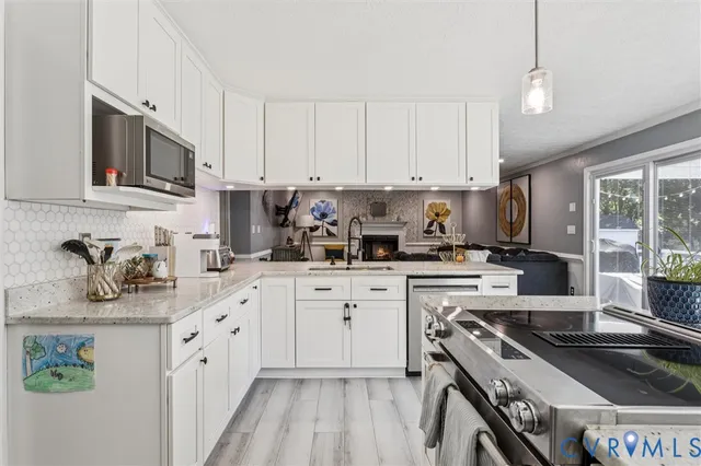 a kitchen with granite countertop a sink stainless steel appliances and white cabinets