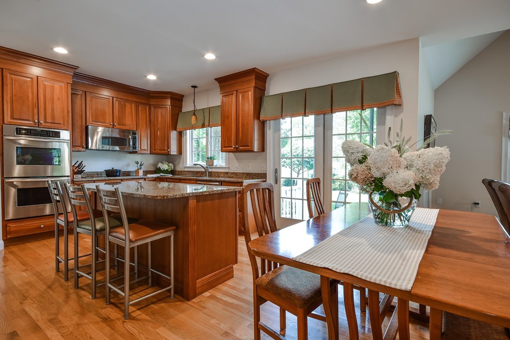 11 Marshall Road Wellesley, MA 02482 - Photo 6 of 18 a kitchen with stainless steel appliances granite countertop a stove top oven a dining table and chairs with wooden floor