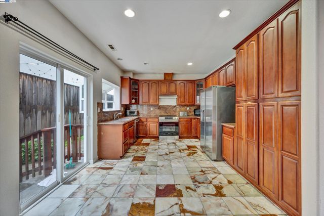 a large kitchen with stainless steel appliances wooden cabinets a stove and a refrigerator