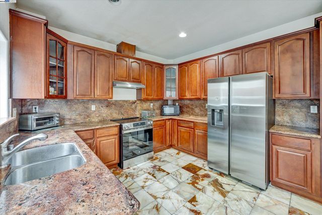 a kitchen with stainless steel appliances granite countertop a refrigerator stove top oven and large window