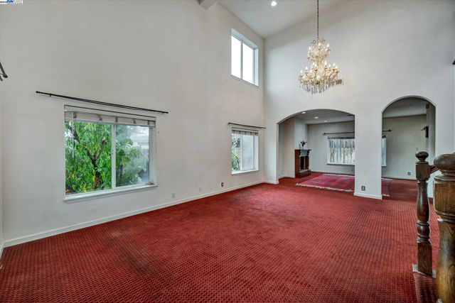 an empty room with windows chandelier and fireplace