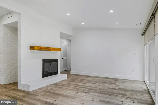 a view of empty room with wooden floor and fireplace