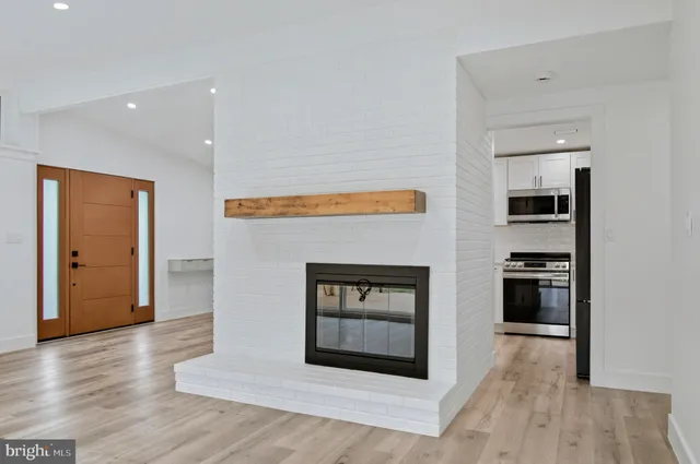 a living room with stainless steel appliances wooden floor and a fireplace