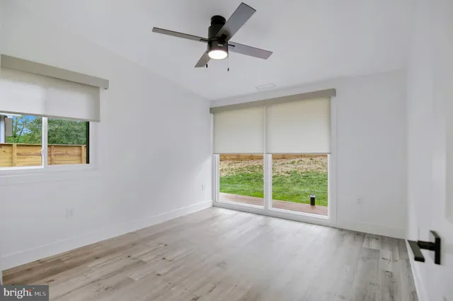 a view of a hallway with wooden floor and a bathroom