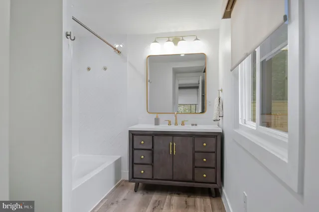 a bathroom with a double vanity sink mirror and bathtub