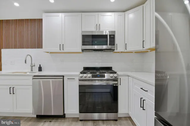 a kitchen with white cabinets and stainless steel appliances