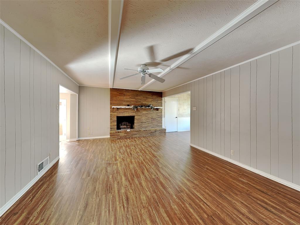13630 Willow Bend Road Dallas, TX 75240 - Photo 4 of 17 an empty room with wooden floor fireplace and windows