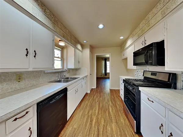 a large kitchen with a stove top oven a sink a microwave and wooden floor