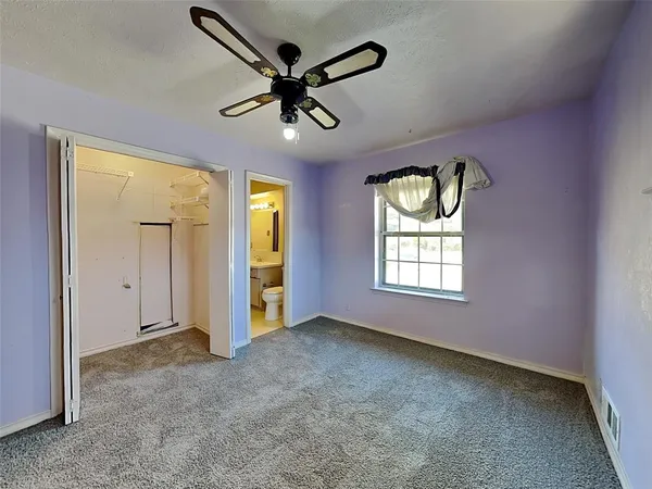 an empty room with ceiling fan and windows