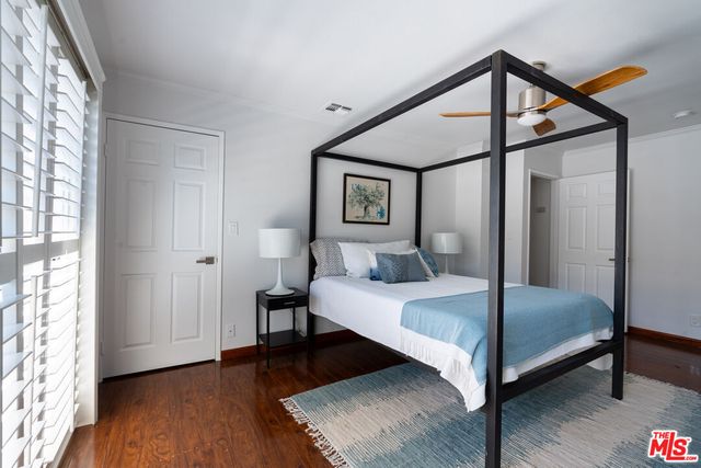 a bedroom with a bed a window and wooden floor