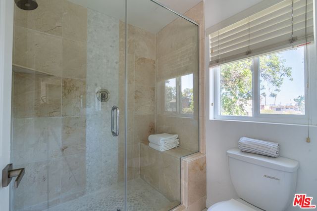 a bathroom with a granite countertop shower a toilet and a sink