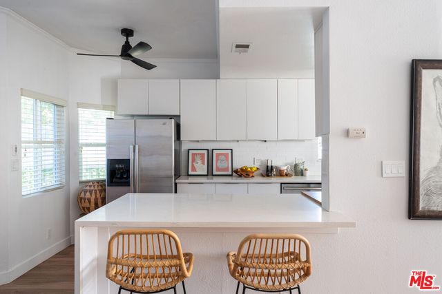 a kitchen with stainless steel appliances granite countertop a refrigerator a stove a sink dishwasher and white cabinets with wooden floor