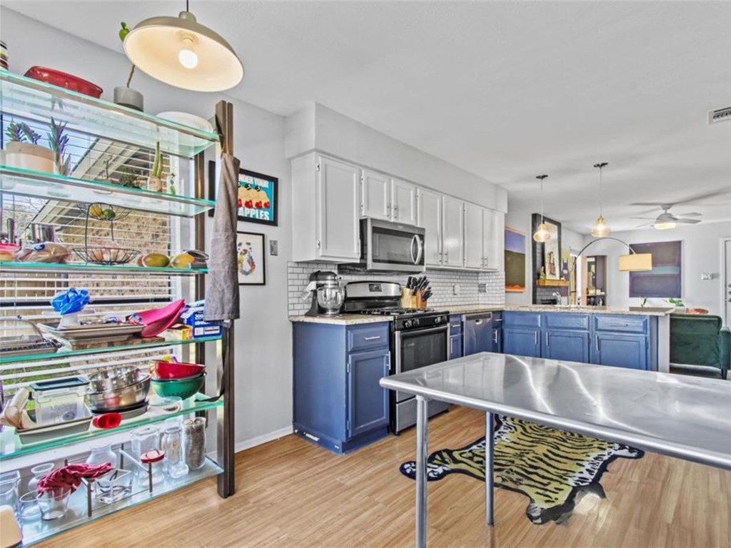 2800 Burleson Road Austin, TX 78741 - Photo 12 of 35 a kitchen with stainless steel appliances granite countertop a sink dishwasher and cabinets with wooden floor