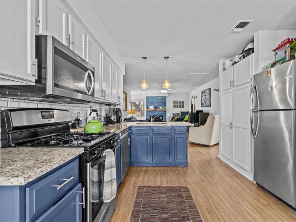 2800 Burleson Road Austin, TX 78741 - Photo 21 of 35 a kitchen with stainless steel appliances granite countertop a stove a sink dishwasher a refrigerator a microwave oven with wooden floor
