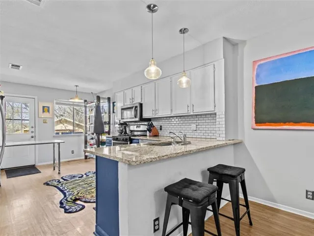 a kitchen with stainless steel appliances granite countertop a sink a stove and a wooden floors
