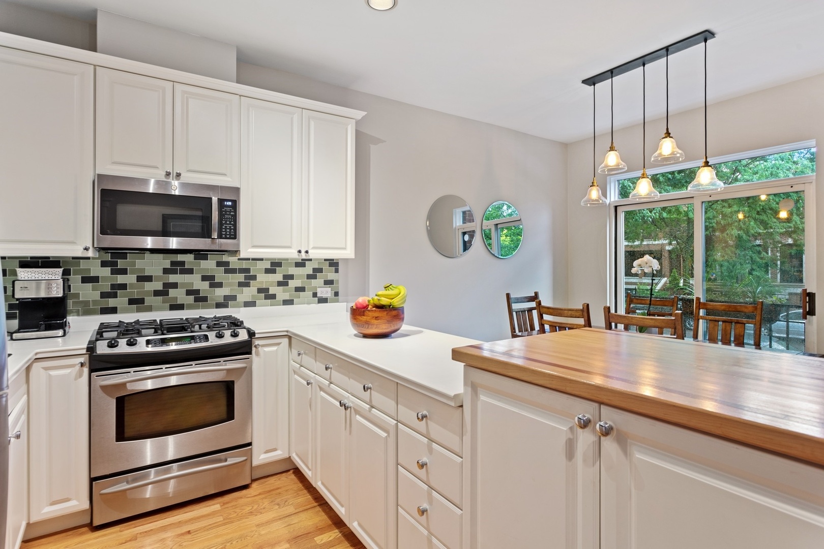 2955 North Racine Avenue, Unit 1A Chicago, IL 60657 - Photo 3 of 29 a kitchen with stainless steel appliances a stove a sink a microwave a stove and white cabinets with wooden floor