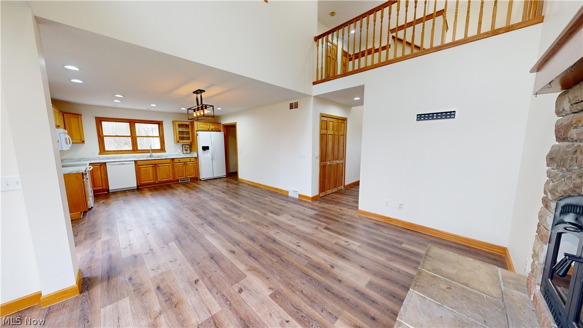 15548 Trask Road Thompson, OH 44086 - Photo 7 of 31 Unfurnished living room with a wood stove, sink, a stone fireplace, light hardwood / wood-style flooring, and a high ceiling