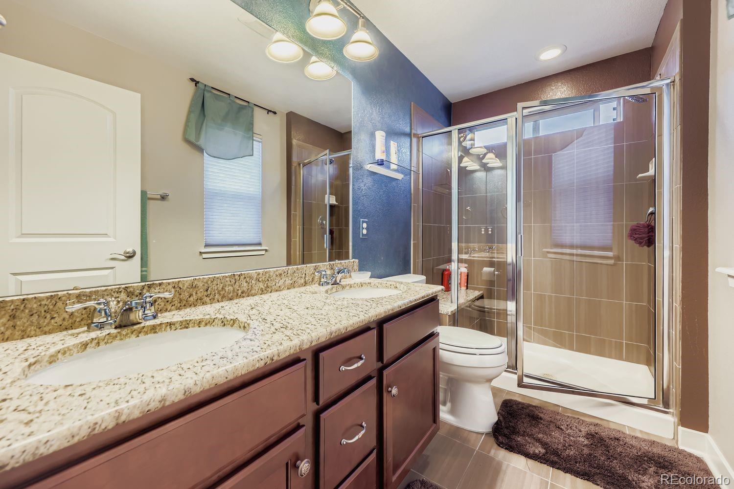 8508 Redpoint Way Broomfield, CO 80021 - Photo 11 of 21 a bathroom with a granite countertop sink a toilet a mirror and shower