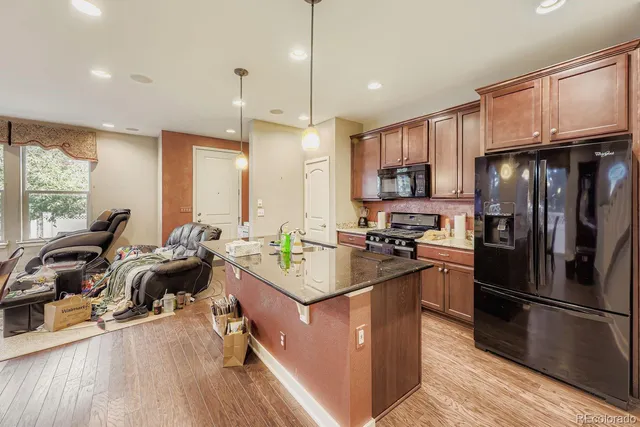 a kitchen with stainless steel appliances granite countertop a refrigerator a stove a sink dishwasher and a microwave with wooden floor