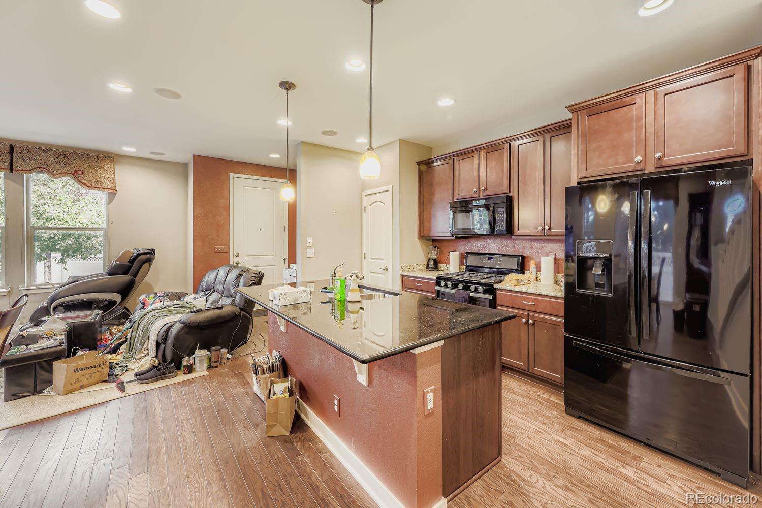 8508 Redpoint Way Broomfield, CO 80021 - Photo 6 of 21 a kitchen with stainless steel appliances granite countertop a refrigerator a stove a sink dishwasher and a microwave with wooden floor
