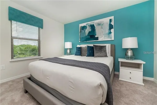 a bedroom with a bed and a lamp on dresser