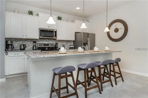 a kitchen with stainless steel appliances a white table chairs and a refrigerator