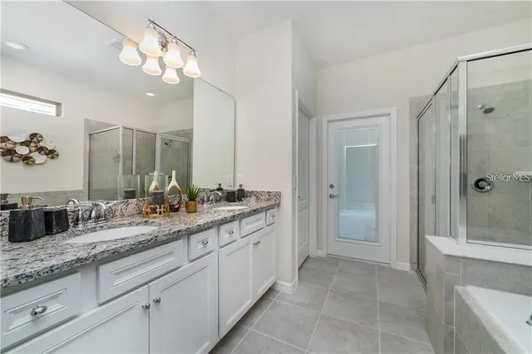 a bathroom with a granite countertop double vanity sink mirror and shower