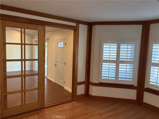 a view of an empty room with wooden floor and a window