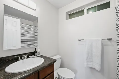 a bathroom with a granite countertop toilet sink and mirror
