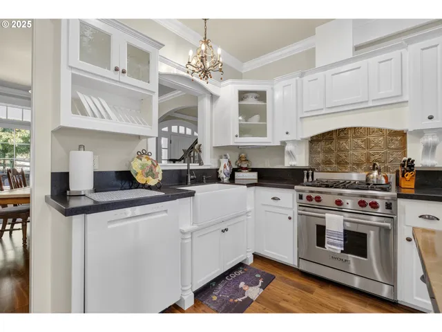 a kitchen with stainless steel appliances granite countertop a stove a sink and white cabinets