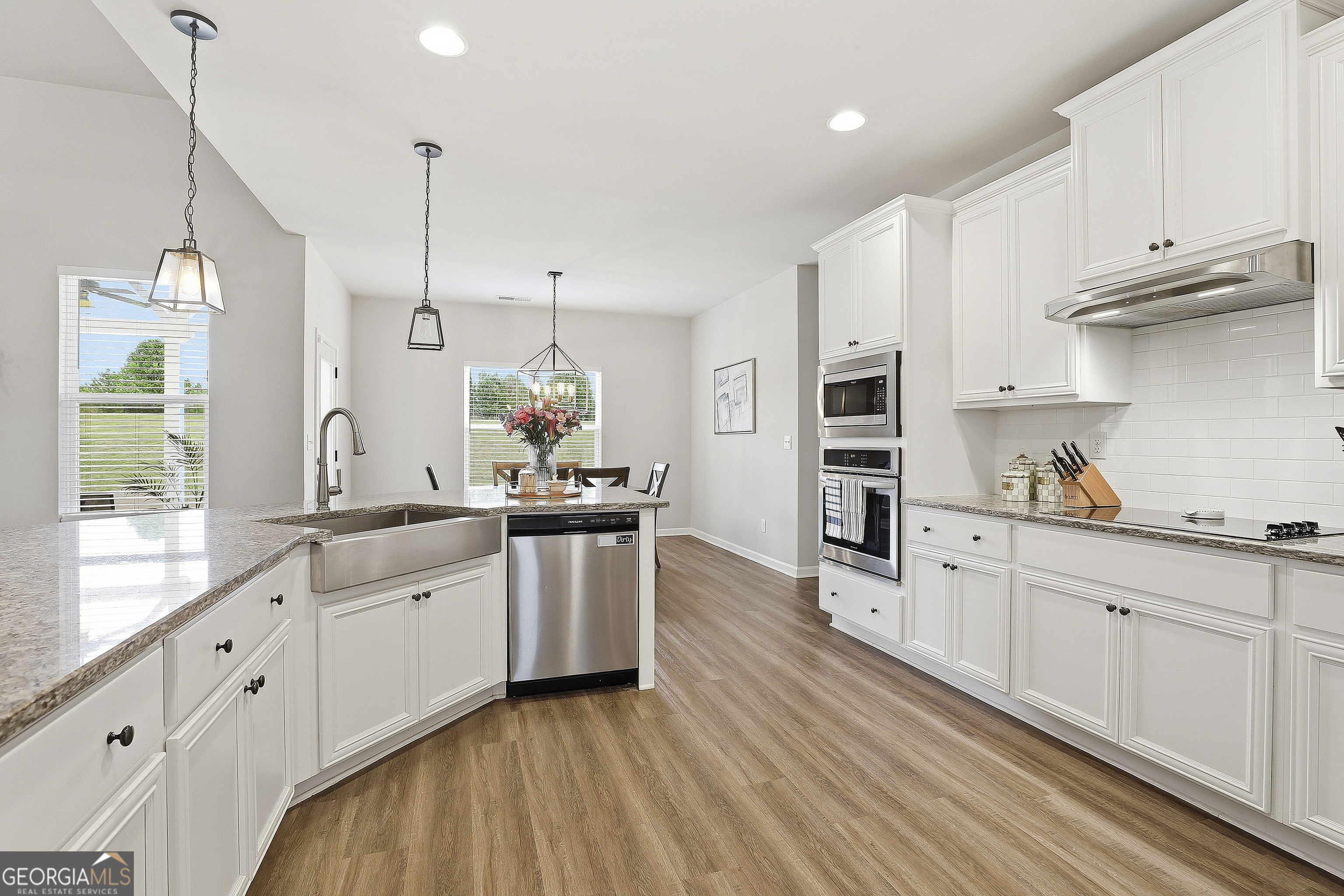 66 Chapman Farm Road Senoia, GA 30276 - Photo 22 of 46 a kitchen with stainless steel appliances granite countertop a sink a stove and white cabinets with wooden floor