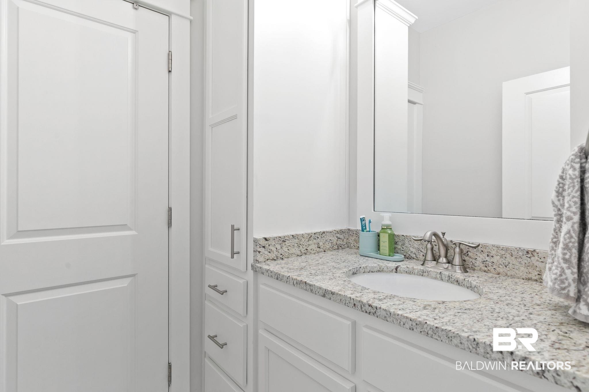 13233 Ibis Boulevard Daphne, AL 36527 - Photo 40 of 100 White vanity with an integrated oval sink, speckled countertop, brushed nickel faucet, and a wall-mounted mirror
