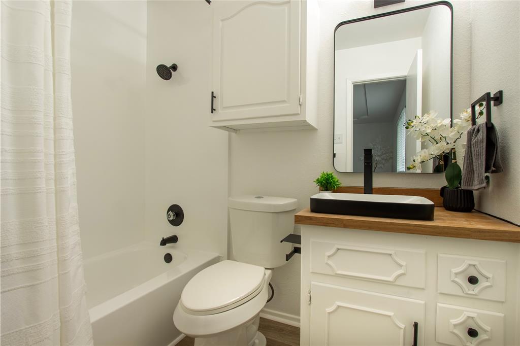 1205 Augusta Road Benbrook, TX 76126 - Photo 18 of 21 Bathroom vanity with a wood-finish countertop, vessel sink, and matte black fixtures