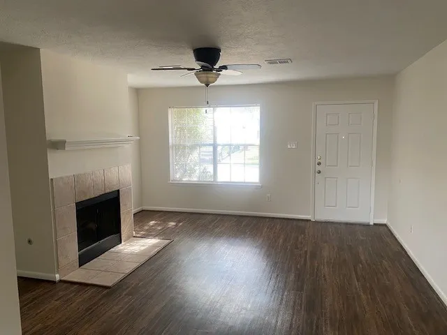 an empty room with wooden floor fireplace and windows