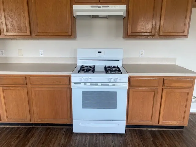 a kitchen with granite countertop cabinets appliances and a wooden floor