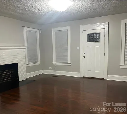 a view of empty room with wooden floor and fireplace