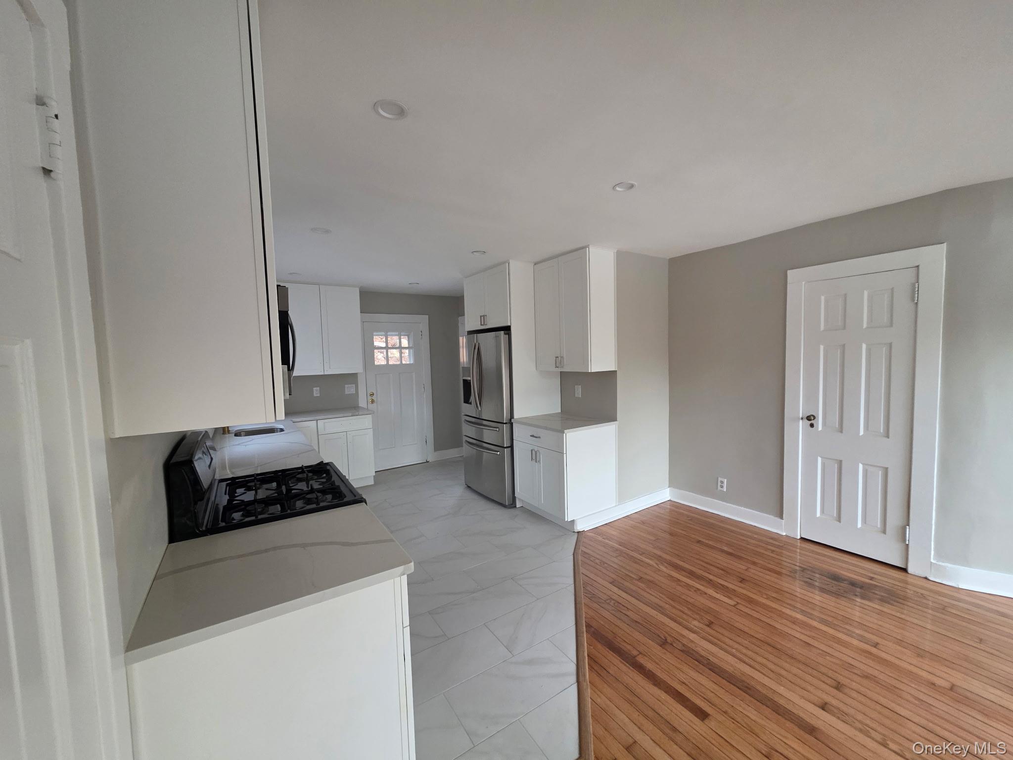 263 South Mountain Road New City, NY 10956 - Photo 15 of 33 Kitchen with white cabinetry, appliances with stainless steel finishes, light stone counters, and light wood-type flooring