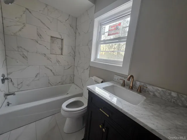 a bathroom with a granite countertop toilet a sink and bathtub