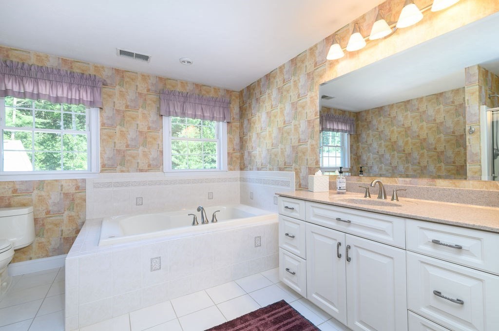 53 Queens Circle Raynham, MA 02767 - Photo 28 of 38 a bathroom with a double vanity sink a mirror and a bathtub