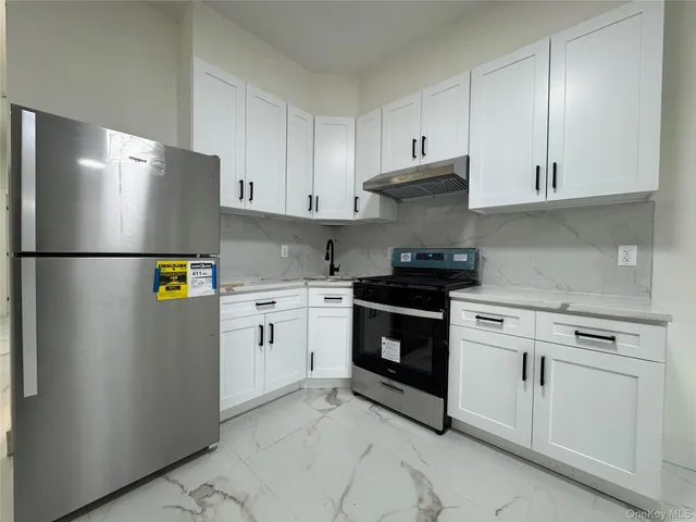 a kitchen with stainless steel appliances white cabinets and a refrigerator