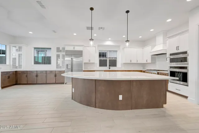 a large kitchen with stainless steel appliances kitchen island a large counter top a stove and a refrigerator