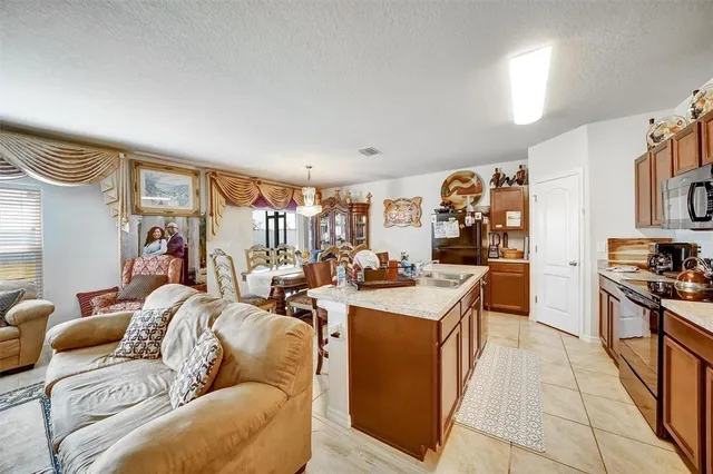 a view of a dining room and livingroom with furniture wooden floor a rug a painting and a chandelier