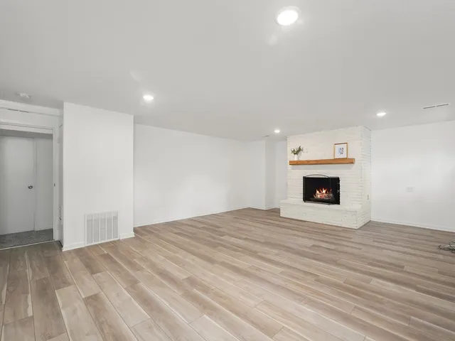 a view of empty room with wooden floor and fireplace