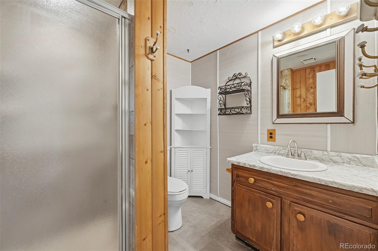 7020 Wildridge Road Colorado Springs, CO 80908 - Photo 34 of 45 a bathroom with a granite countertop sink mirror and a shower
