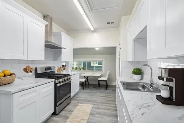 a kitchen with a sink dishwasher stove and white cabinets with wooden floor