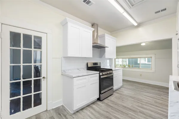 a kitchen with stainless steel appliances a stove a sink and white cabinets