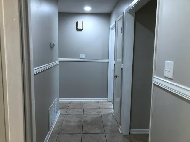 a view of a refrigerator in kitchen and an empty room in wooden floor