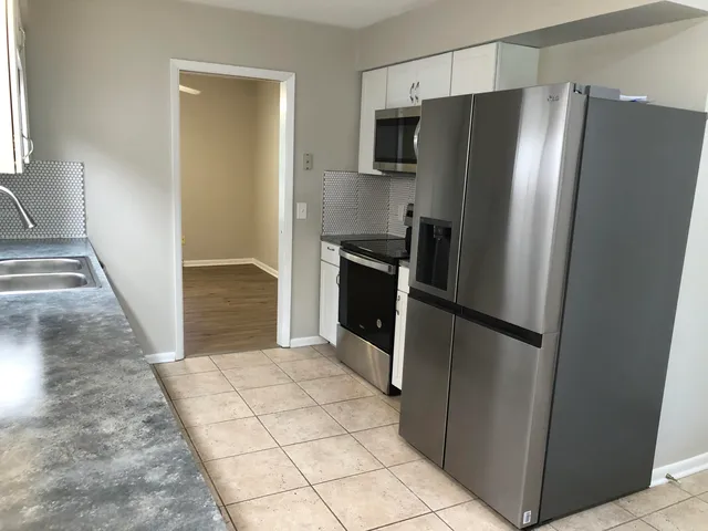 a kitchen with kitchen island granite countertop a sink a stove and cabinets