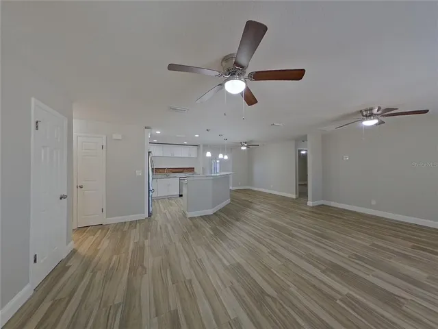 a view of empty room with wooden floor and ceiling fan